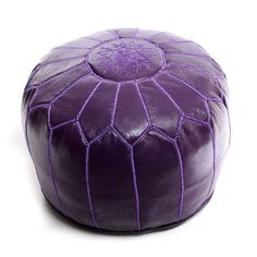 a large purple leather poufce sitting on top of a white floor