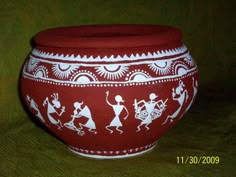 a red and white painted pot sitting on top of a table