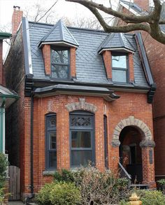 a red brick house with two story windows and a yellow fire hydrant in the front yard