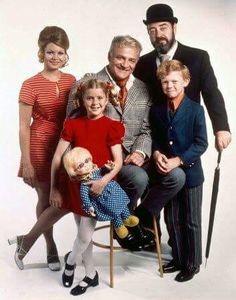 a group of people posing for a photo with a child on a chair and an adult holding a cane