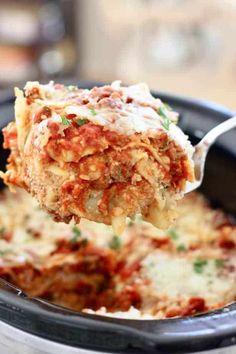 a spoon full of lasagna casserole being lifted from a slow cooker