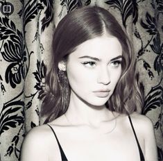 a black and white photo of a woman in front of a curtain with her eyes closed