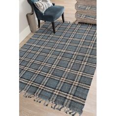 a blue chair sitting on top of a wooden floor next to a rug with tassels