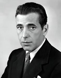 a black and white photo of a man in a suit with his hand on his chest