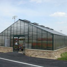 a large greenhouse sitting on the side of a road next to a grass covered field