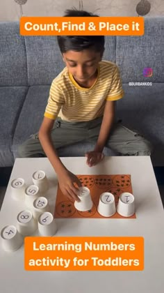 a young boy sitting at a table with numbers and letters on it, in front of him