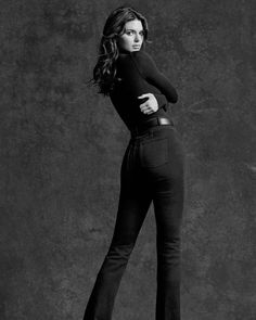 black and white photo of woman in high waisted jeans posing with her hands on her hips