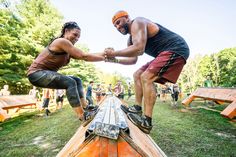 a man and woman are holding hands on top of a log