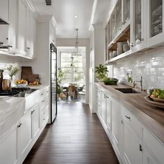 a long narrow kitchen with white cabinets and wood flooring, along with wooden counter tops