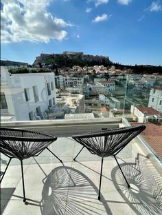 two chairs sitting on top of a roof next to each other in front of a city