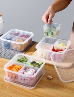 three plastic containers filled with food on top of a wooden table next to a cutting board