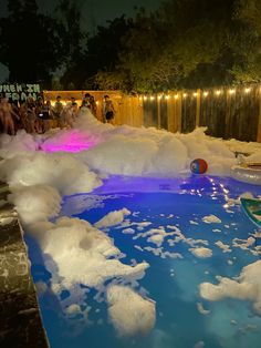 people are gathered around an inflatable pool with white foam on the bottom and blue water