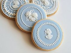 four decorated cookies with blue icing and white trimmings are on a table