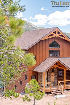 a large wooden house sitting on the side of a hill next to a pine tree