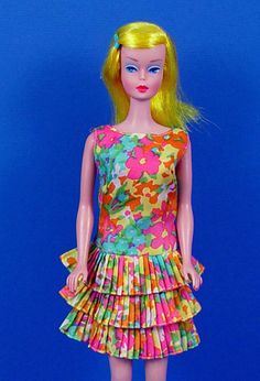 a barbie doll with yellow hair wearing a colorful dress and shoes on a blue background