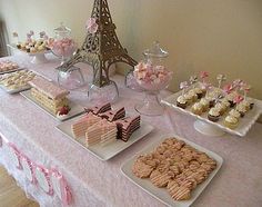 a table topped with cakes and desserts next to a tall eiffel tower