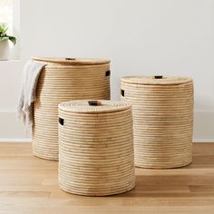 three woven storage baskets sitting on top of a wooden floor next to a potted plant