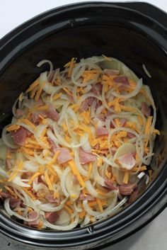 the food is being cooked in the crockpot with cheese and ham on top