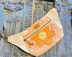 an orange and white purse sitting on top of a jean jacket