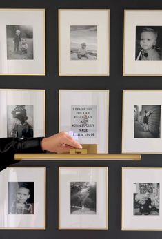 a person's hand on a shelf in front of many framed pictures and photos