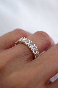 a woman's hand with a diamond ring on her left hand, showing the band and side stones