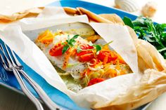 a paper bag filled with food sitting on top of a blue plate next to vegetables