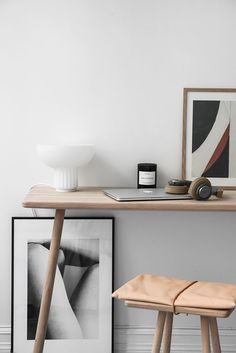 a wooden table with two stools next to it and a painting on the wall