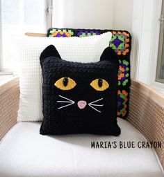 a black cat pillow sitting on top of a white chair