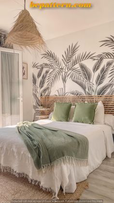 a large bed sitting in a bedroom next to a wall with palm leaves on it