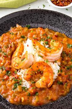 a black plate topped with shrimp and rice