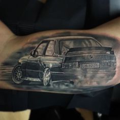 a man's arm with a black and grey tattoo of a car on it