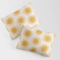 two yellow and white pillows with gold sun print on the front, one is square