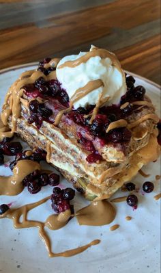 a piece of cake on a plate with whipped cream and chocolate sauce drizzled around it