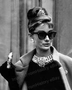 an old photo of a woman wearing sunglasses and holding a cake in her hand,