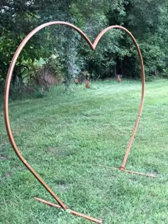 a heart shaped metal sculpture in the grass