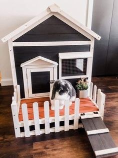 a dog house made out of pallets with a cat sitting in the top window