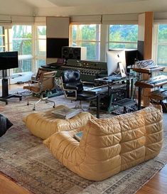 a living room filled with lots of furniture and electronics on top of a wooden floor