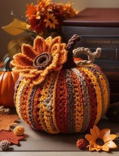 a crocheted pumpkin sitting on top of a table next to books and flowers