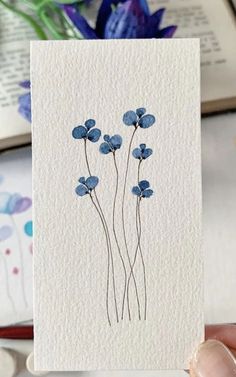 a person holding up a card with blue flowers on it