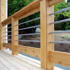 a wooden deck with metal railings and trees in the background