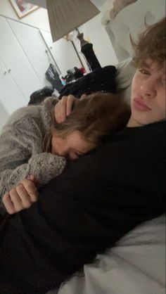 a man and woman cuddle together on a bed