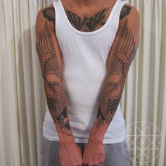 a man with tattoos on his arms and arm is standing in front of a curtain