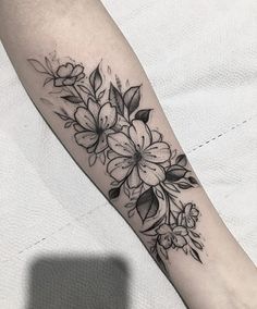 a black and white flower tattoo on the left arm, with flowers in it's center