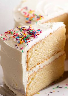 a slice of cake with white frosting and sprinkles