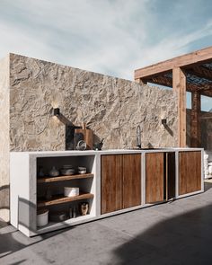 an outdoor kitchen with stone walls and wooden cabinets