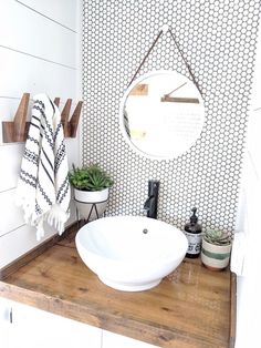 a white sink sitting on top of a wooden counter next to a potted plant