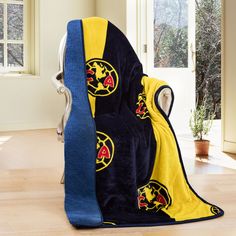 a blue and yellow blanket sitting on top of a chair in front of a window