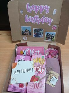 an open birthday box filled with lots of pink and purple items on top of a wooden table