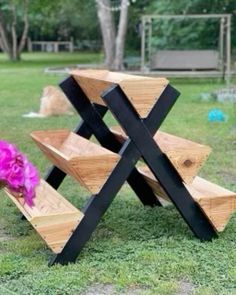 a wooden bench sitting on top of a lush green field next to a pink flower