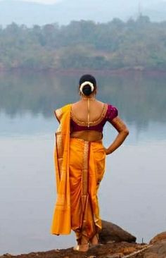 a woman standing on top of a rock next to a body of water